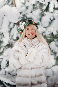 在寒冷的冬天森林里穿着白色皮草大衣的女人的画像 在白雪覆盖的冬季森林里 头戴花环的女孩 皮毛大衣 假期图片