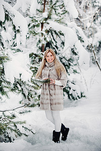 在寒冷的冬天森林里穿着白色皮草大衣的女人的画像 白雪覆盖的冬季森林里的女孩 新年快乐 雪花图片