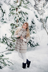 在寒冷的冬天森林里穿着白色皮草大衣的女人的画像 白雪覆盖的冬季森林里的女孩 帽子图片