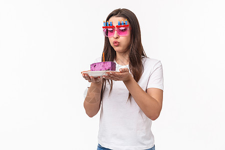 娱乐 乐趣和假期的概念 可爱有趣的生日女孩在生日蛋糕上吹灭蜡烛 戴派对眼镜 梦想成真 白色背景 折扣 可爱的图片