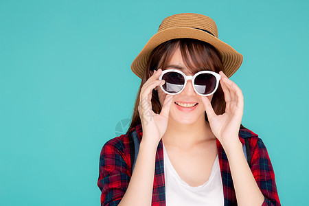 美丽的肖像年轻亚洲女性戴着帽子 戴着太阳镜 自信地微笑着享受暑假之旅 在蓝色背景下与世隔绝 亚洲旅游女孩对旅行感到高兴 时髦的 图片