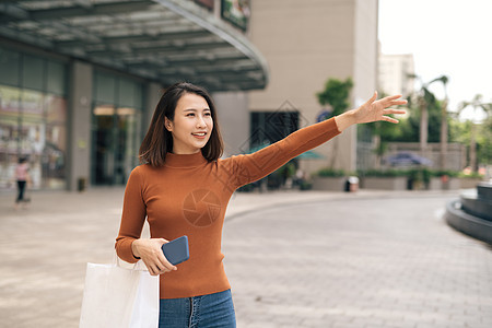 带着购物袋在商场外搭计程车的年轻亚洲女子 快乐的 街道图片