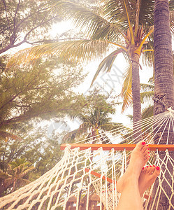 在海底 棕榈树和日落背景的吊床上 女性双腿被吊在吊床上 脚图片