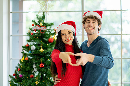 两对男女青年用手来象征心脏的象征 他们带着快乐的圣诞节装饰住在房间里 欢欣鼓舞地庆祝圣诞节图片