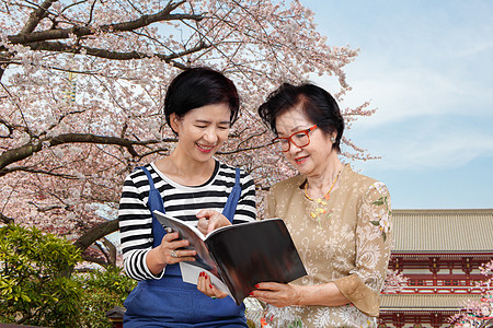 与女儿一起阅读旅行指导手册的年长妇女图片