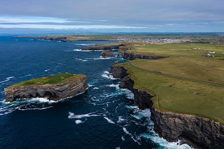 爱尔兰著名的旅游里程碑莫赫克里夫 Moher Cliff 的美丽绿色山峰的空中全景观 海浪白天在云层下撞击岩石图片