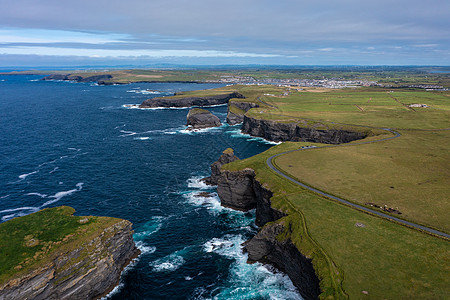 爱尔兰著名的旅游里程碑莫赫克里夫 Moher Cliff 的美丽绿色山峰空中景象 海浪白天在云层下撞击岩石图片