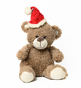 棕色可爱泰迪熊坐在红色的圣诞帽上 白色背景图片