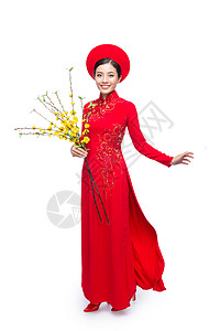春节出行一位美丽的亚洲妇女穿着传统节服Ao Dai的肖像 手持Hoa Mai树花朵 Tet节日 月亮新年 手势 女性背景
