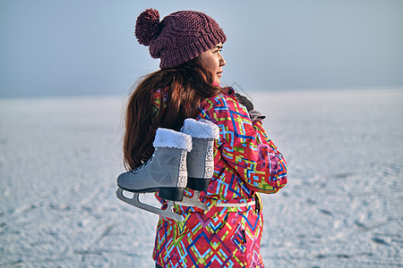 一个女人在冰冻湖上滑雪后 肩上握着溜冰鞋 衣服 自然图片