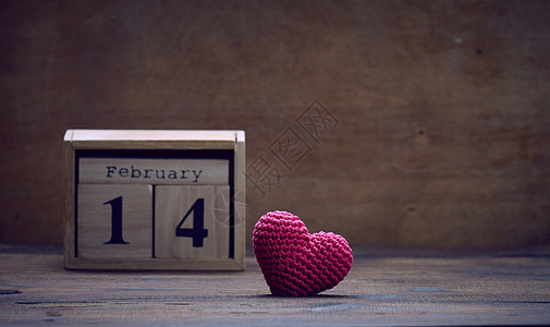 2月14日木制日历和红编织心脏 棕色背景 天图片