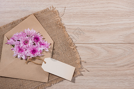 空白的白纸标签 上面有棕色信封和木制桌上的粉红色花朵 商业 空的图片
