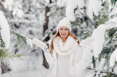 一个穿着白色衣服的女人在寒冷的冬天森林里的画像 在白雪皑皑的冬季森林里 一个头戴白帽子的女孩 树 艺术图片