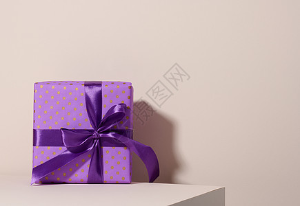 装在节日紫色纸的盒子里 并绑上蜜蜂背景上的丝带 生日礼物 惊喜 天 圣诞节图片