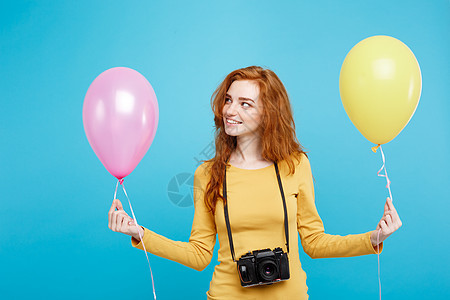 生活方式和派对概念 — 特写肖像年轻漂亮迷人的姜红色头发女孩 带着彩色气球和老式相机 蓝色柔和的背景 复制空间 潮人 美丽图片