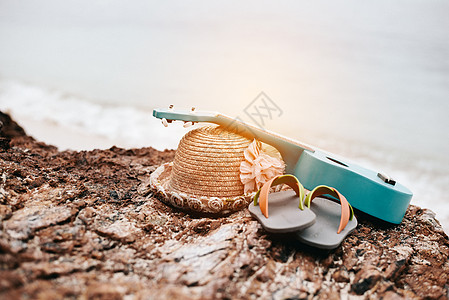 在海滩度假的女人配饰 夏威夷四弦琴和凉鞋和帽子在海边的岩石上 热带和季节概念 夏季和假日主题 放松和自然主题图片