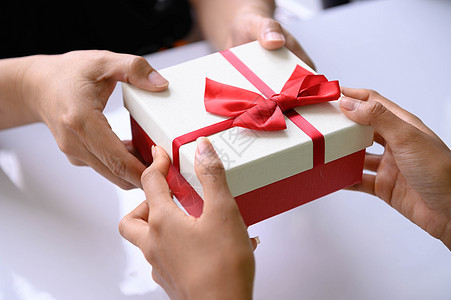在圣诞节和新年节互相赠送带红丝带的礼品盒的手的特写 男人给女人惊喜 假期和活动 年终派对约会惊喜礼盒 生日 家庭图片