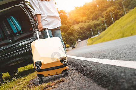 黄色手提箱拖着行李手提箱单独公路旅行装载到 SUV 汽车的后视图 人们的生活方式和度假理念 自然和夏季主题 有冒险运输的女孩图片