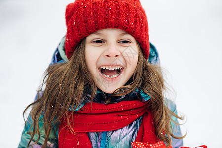 关闭快乐可爱的女孩看着相机 微笑着白雪皑皑的森林的背景 积极的孩子 肖像拍摄 外部 寒冬 寒冷的天气 霜 雪图片