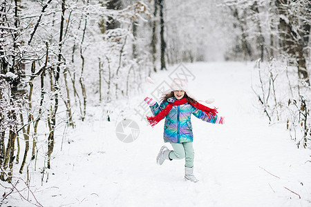 在一个美丽的白雪皑皑的公园里奔跑的滑稽笑儿童女孩 快乐的女孩在大自然中的冬天散步玩耍 表达积极性 真正明亮的情绪 微笑图片