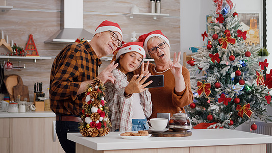外孙女在圣诞节节日庆典期间与祖父母一起使用自拍手语图片