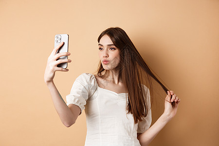 时尚的年轻女子玩头发和自拍智能手机 为社交媒体拍照 站在蜜蜂背景上 fege friend 微笑 伙伴图片