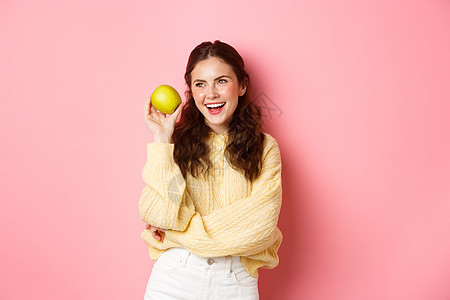 医疗保健和生活方式的概念 笑得开朗的女人 脸上露出完美的白色笑容和青苹果 吃着健康的水果 站在粉红色的背景下 女孩 假期图片