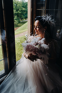 新娘穿着婚纱和花束 坐在开着的旧窗前看 婚礼图片