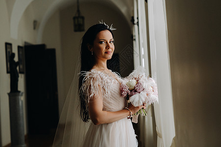 新娘穿着婚纱和花束 站在旧窗前的窗户和外观 裙子 婚礼图片
