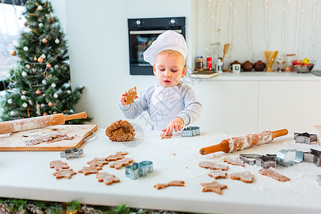 可爱的小男孩做姜饼 切饼干的姜面包面团 厨房图片