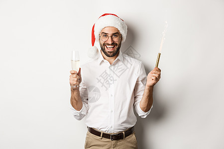 冬假和节假日与庆典 长胡子帅哥有新年晚会 拿着烟花火花和香槟 穿着圣塔帽 白背景 购物 冬天图片