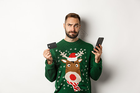 新年 在线购物和圣诞节概念 有思想的人使用手机和信用卡 考虑礼物 站在白色背景上 庆祝 银行图片