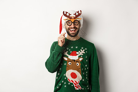 圣诞节和假期的概念 快乐的留着胡须的男人庆祝圣诞节 拿着派对面具 戴着圣诞帽 微笑着惊讶地站在白色背景上 美丽的 大胡子图片