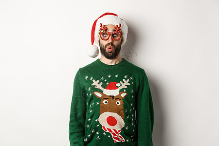 圣诞假期 庆祝的概念 在派对眼镜和圣塔帽子上惊讶的家伙 看着低沉的欢笑 站在白色背景之上 情感 有趣的图片