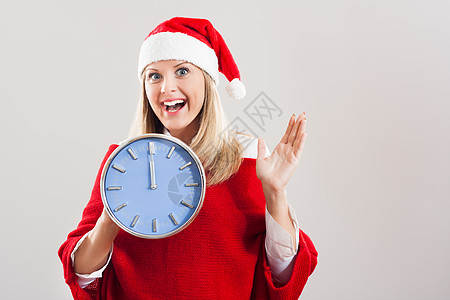 快乐的女士与圣诞老人帽子 握着时钟图片