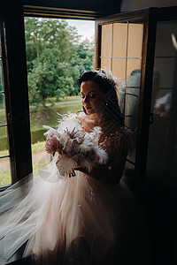 新娘穿着婚纱和花束 坐在开着的旧窗前看 新娘捧花图片