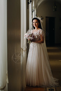 新娘穿着婚纱和花束 站在旧窗前的窗户和外观 快乐的 优雅图片