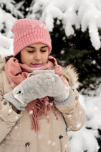 穿着温暖冬衣的漂亮女人 拿着茶杯喝热茶或雪天户外咖啡 温暖的 季节图片