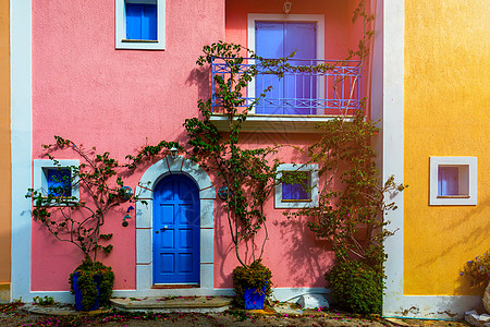 凯法利尼亚岛阿索斯的传统街道上有带鲜花的希腊房屋 Assos 村的传统色彩缤纷的希腊房屋 盛开的紫红色植物花 凯法利尼亚岛 希腊图片