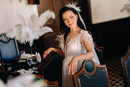 一个穿着婚纱的时装新娘 在餐桌上披着羽毛的餐厅内衣里面 女孩 假期图片