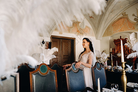 一个穿着婚纱的时装新娘 在餐桌上披着羽毛的餐厅内衣里面 复古的 婚姻图片