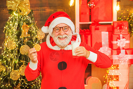 圣诞老人-留着胡子的滑稽前辈 家里的圣诞老人 圣诞老人在平安夜吃饼干和喝牛奶 圣诞老人享用服务的姜饼蛋糕和牛奶图片