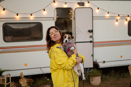 红头发的高加索女人抱着一只狗 住在马达屋里 乘拖车旅行 旅游 秋天图片