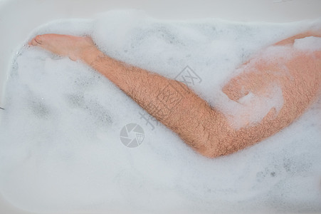 一个男人正在放松地洗澡的有趣照片 泡泡浴中男性脚的特写镜头 顶视图 家 幽默图片