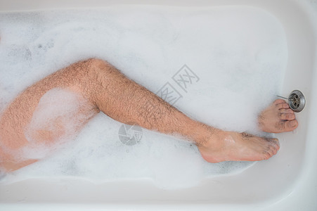 一个男人正在放松地洗澡的有趣照片 泡泡浴中男性脚的特写镜头 顶视图 淋浴 关心图片