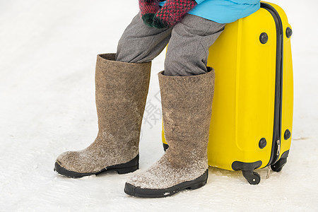 冬天 一个穿有感觉靴子的女孩 在寒冷的雪天坐在手提箱上 行李 游客图片