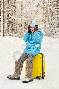 冬天 一个穿有感觉靴子的女孩 在寒冷的雪天坐在手提箱上 游客 自然图片