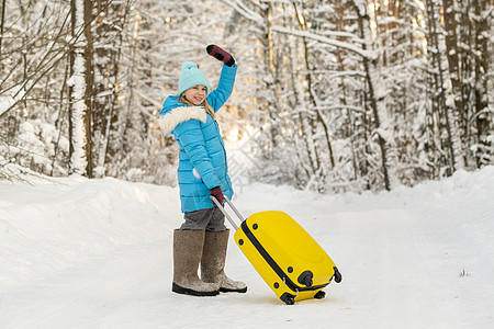 在寒冷的雪天 一个身穿脚靴的冬天女孩 带着手提箱去 天气 游客图片