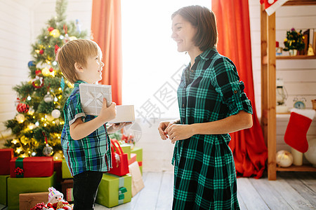 快乐的家庭妈妈和儿子在圣诞节冬天阳光明媚的早晨在装饰圣诞树和礼物的圣诞庆祝室里 父母 女孩图片