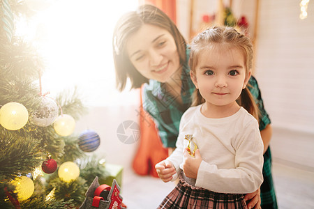 快乐的家庭妈妈和女儿在一个圣诞冬天阳光明媚的早晨 在装饰圣诞树和礼物的圣诞庆祝室里 感情 庆典图片